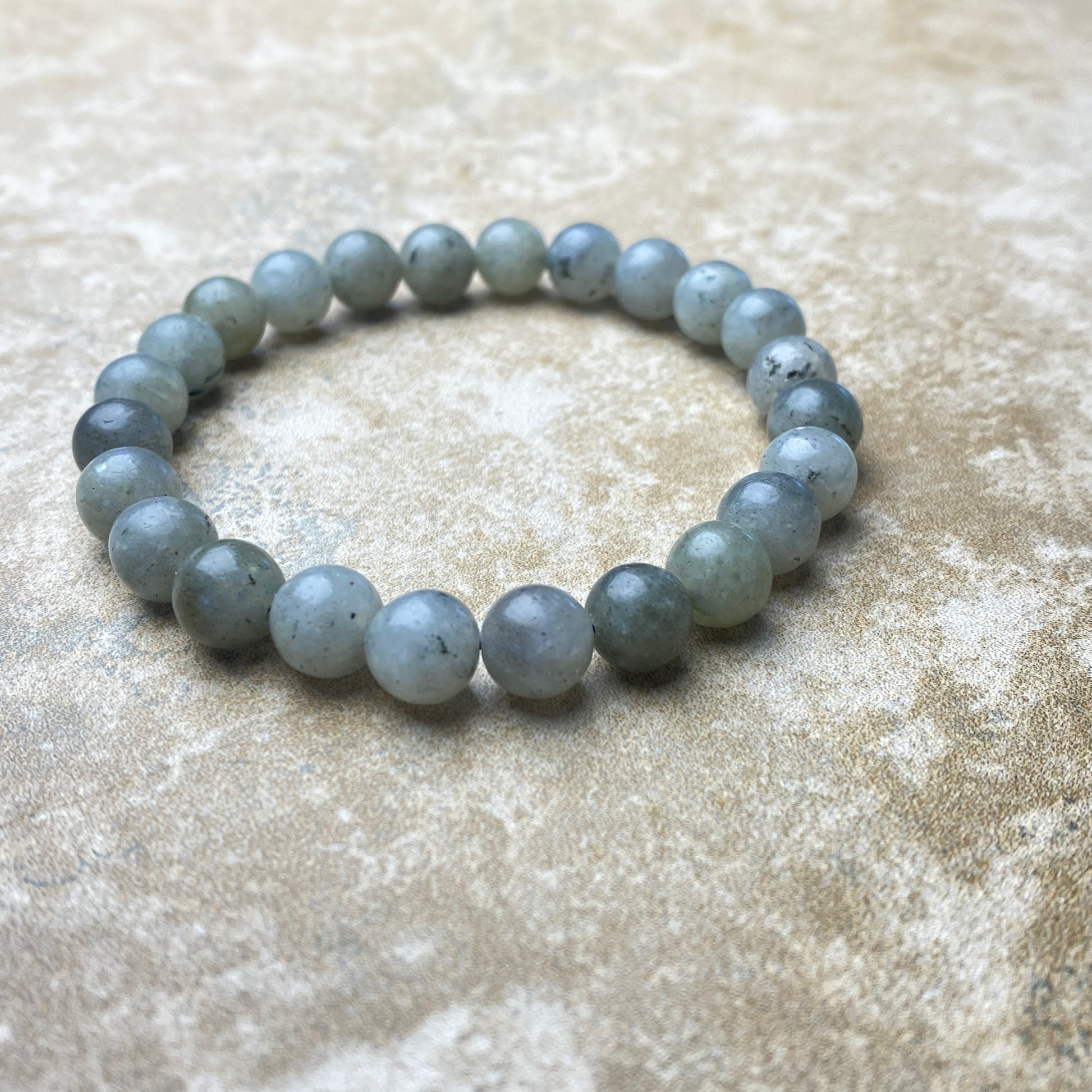 Gray beaded bracelet on a textured beige surface