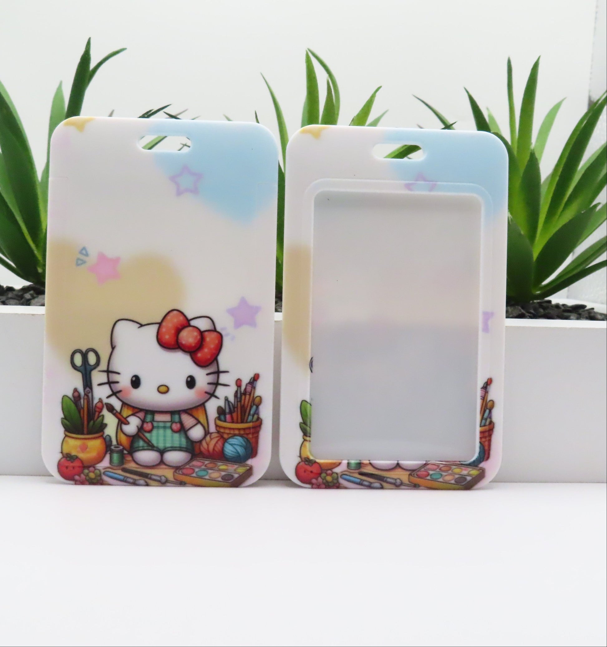 Two phone cases with a cartoon character and colorful design on a white surface with plants in the background.