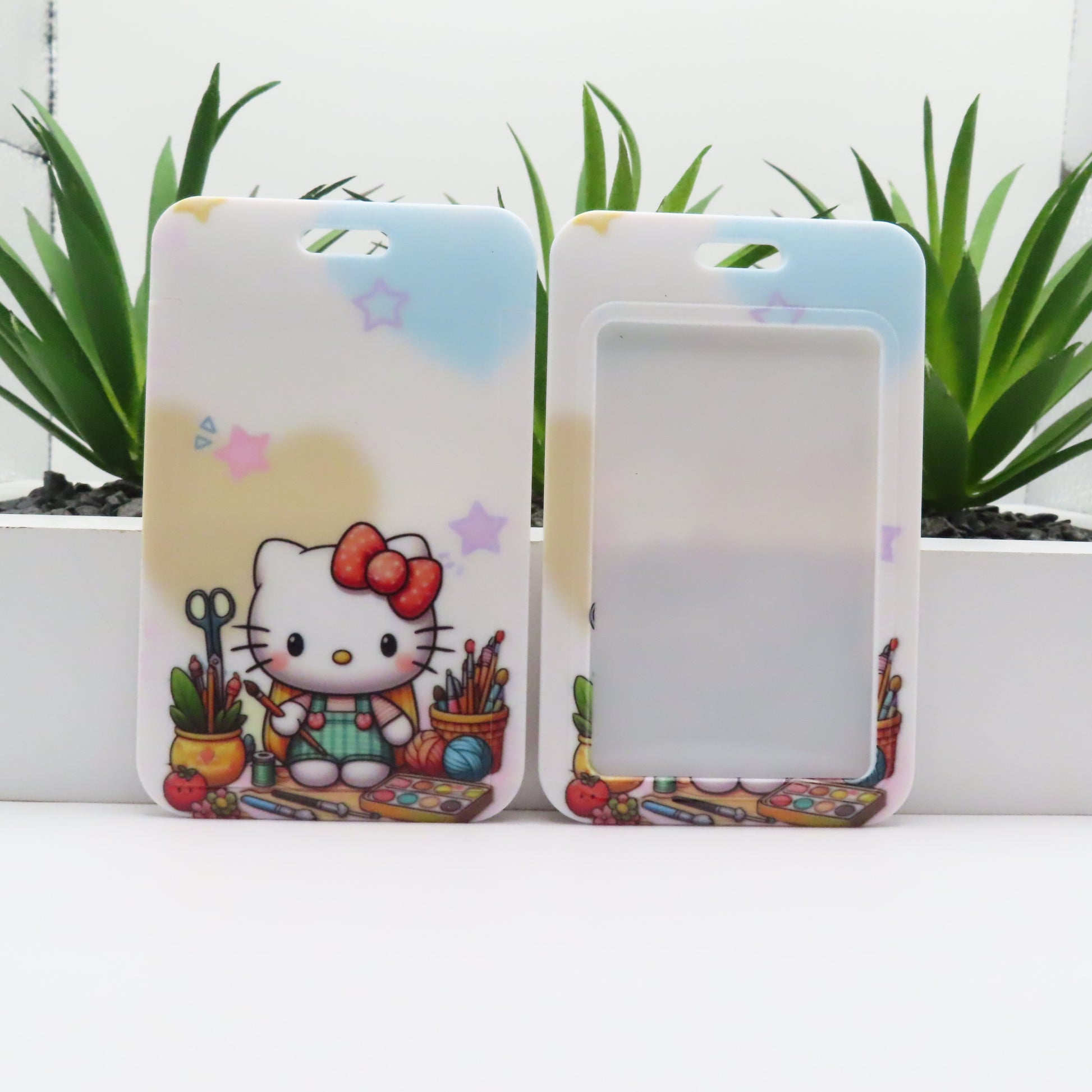 Two phone cases with a cartoon character and colorful design on a white surface with plants in the background.