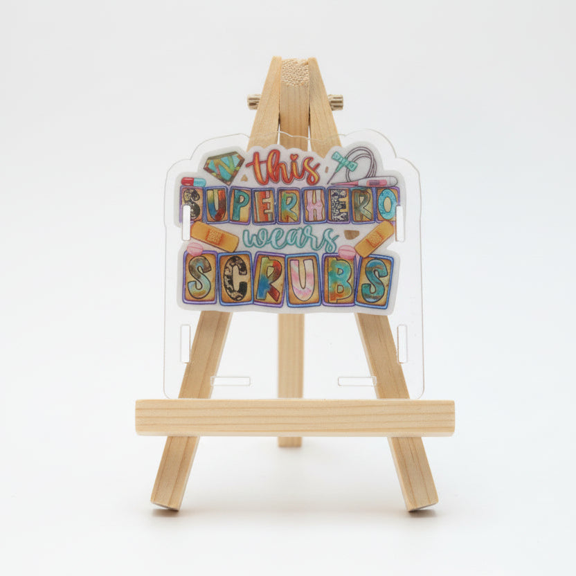 Sticker with colorful text 'This superhero wears scrubs' on a white background