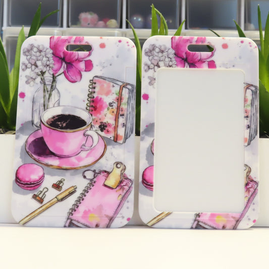 Two phone cases with floral and tea design on a white surface with plants in the background.
