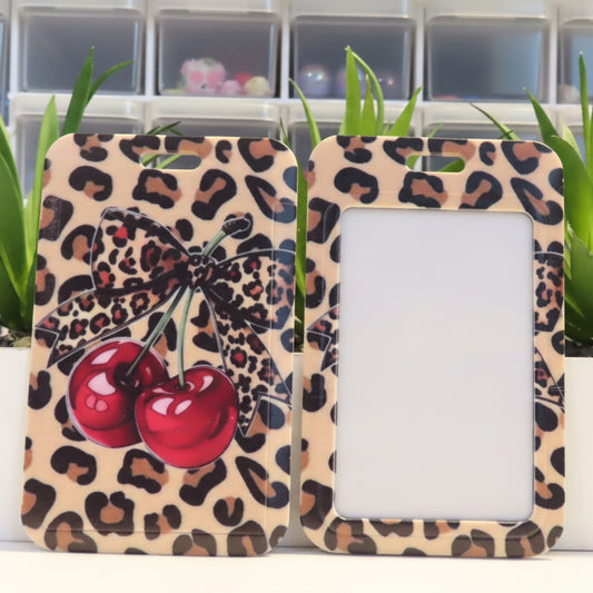 Leopard print picture frame with cherry design on a white surface with plants in the background