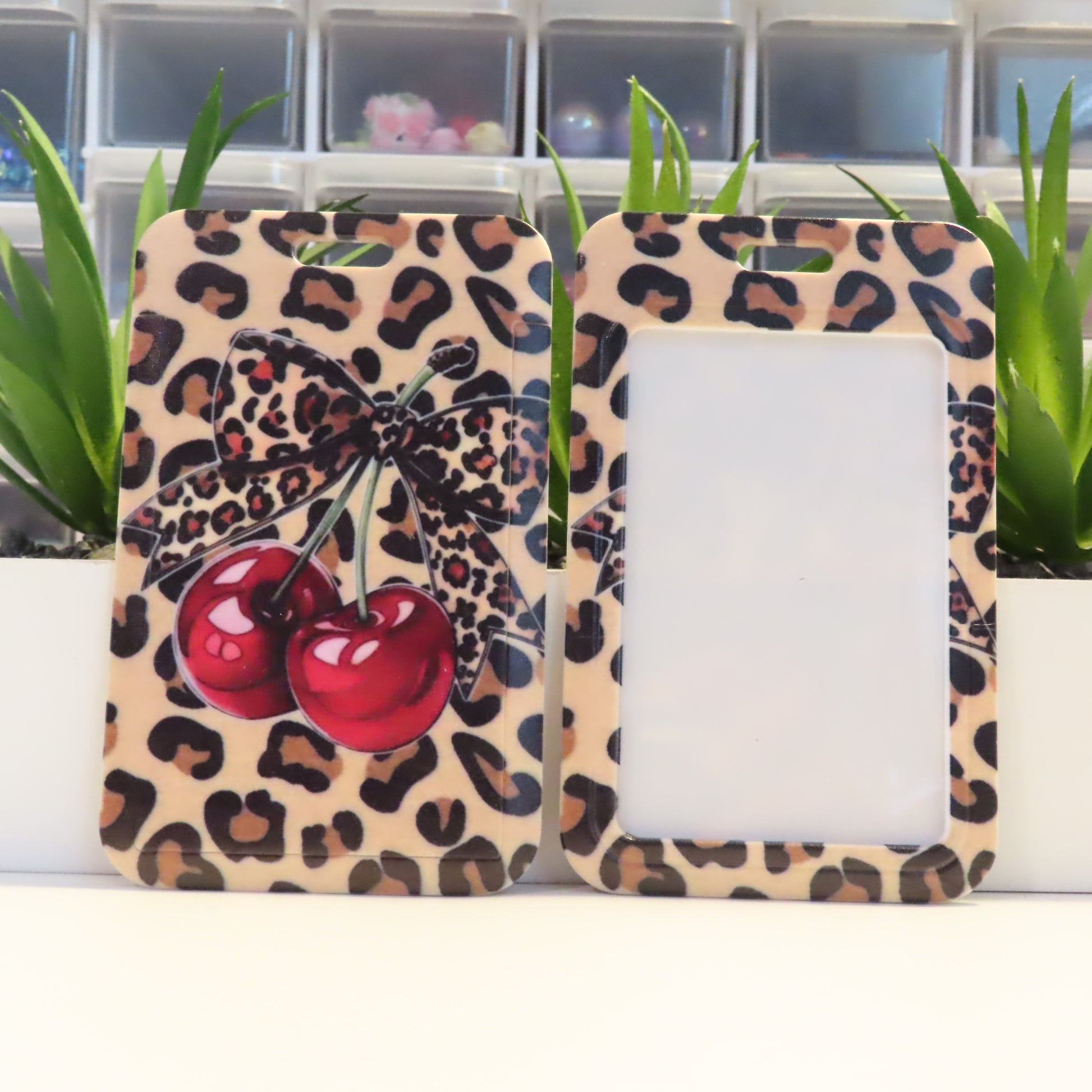 Leopard print picture frame with cherry design on a white surface with plants in the background
