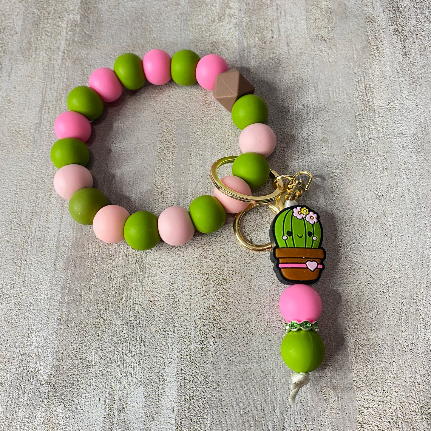 Beaded bracelet with a cactus charm on a textured surface