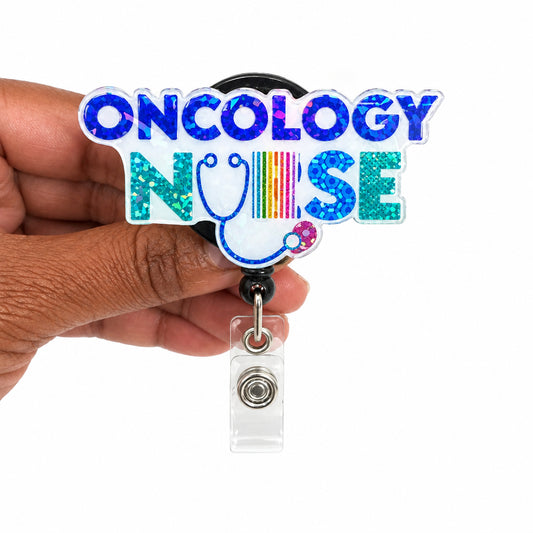 A hand holding a clear acrylic retractable badge reel featuring a 'ONCOLOGY NURSE' design with a stethoscope and colorful holographic lettering, set against a plain white background.
