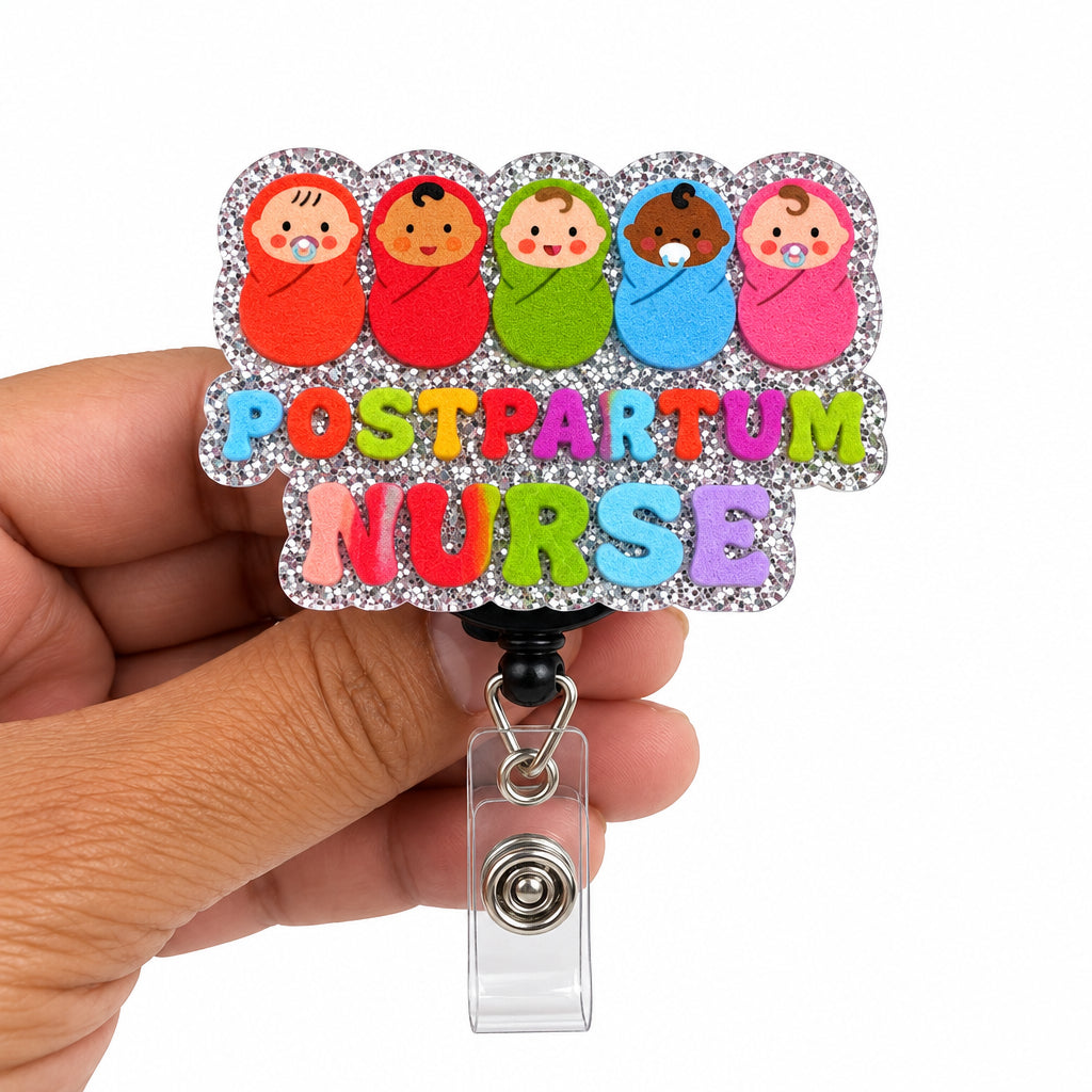 A hand holding a glittery 'POST FAIRTYH NURSE' badge reel. The badge features cartoon baby figures swaddled in red, green, blue, and pink blankets, with the text 'POST FAIRTYH NURSE' in colorful glitter letters.