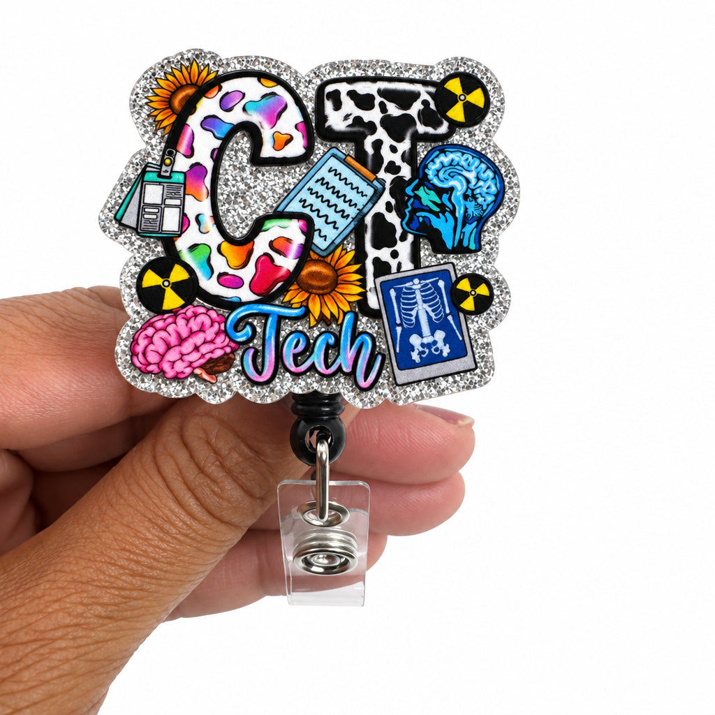 A hand holding a silver glitter retractable badge reel featuring a colorful 'C Tech' graphic with brain, DNA, and x-ray illustrations.