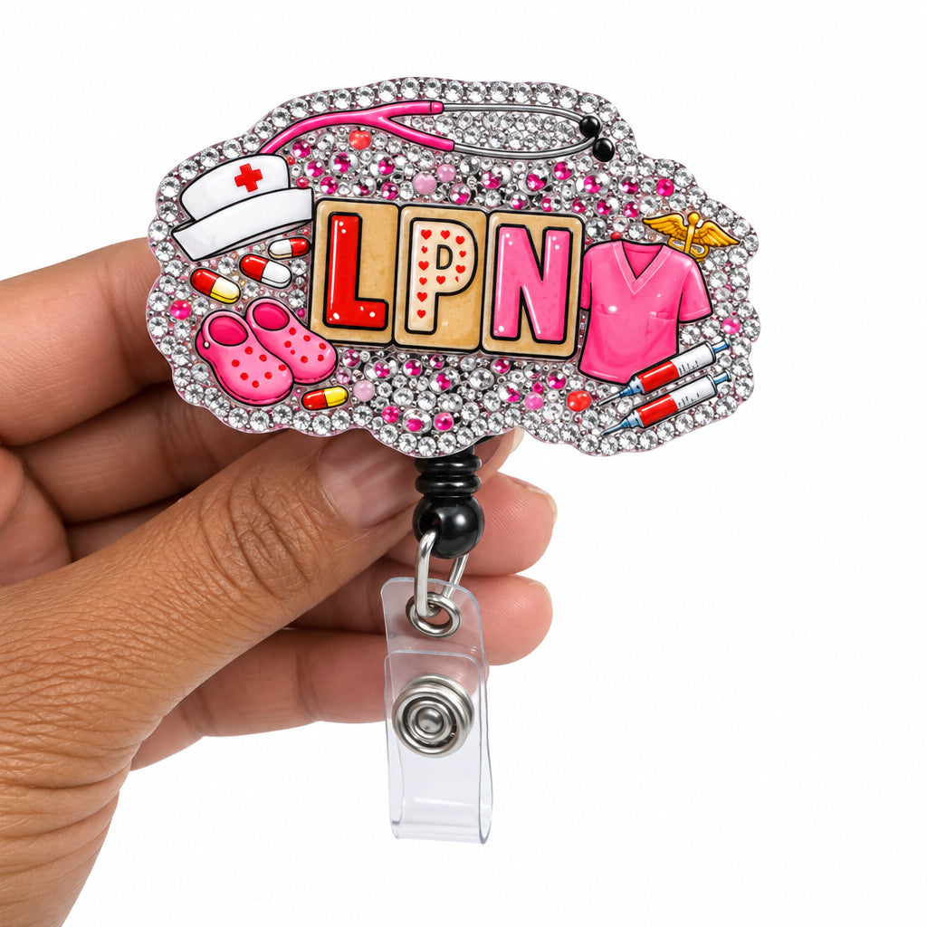 A hand holding a custom acrylic badge reel featuring the letters 'LPN' in yellow with pink glitter accents, surrounded by pink nail polish bottles, a stethoscope, and a pink heart, on a plain white background.
