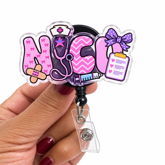 A hand holding a clear acrylic retractable badge reel sign spelling 'NICE' with medical-themed illustrations including a stethoscope, band-aid, clipboard, and pink chevron lettering, against a plain light background.