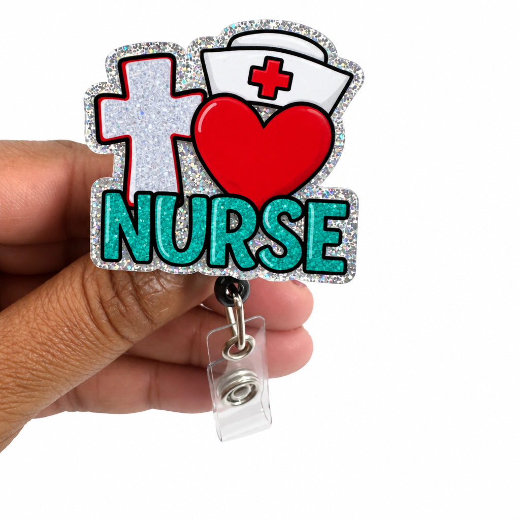 A hand holding a glittery 'I ♥ NURSE' badge reel. The badge features a silver glitter background with a silver cross, a white nurse hat with a red cross, a red heart, and green 'NURSE' text.