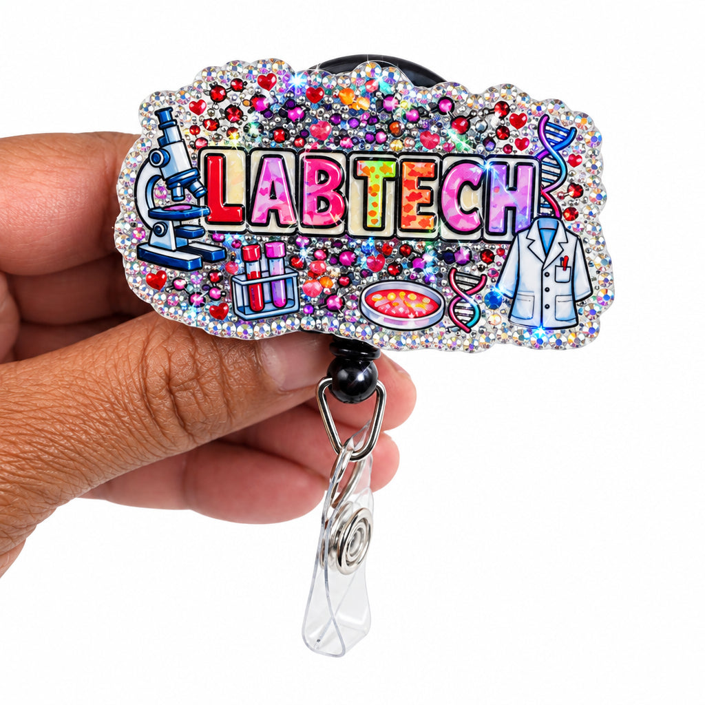 A hand holding a custom holographic acrylic badge reel with the word 'LABTECH' in colorful letters, decorated with rhinestones and small sci-fi illustrations, on a plain white background.