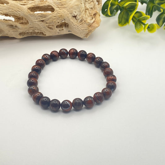 Beaded bracelet on a white surface with natural elements in the background