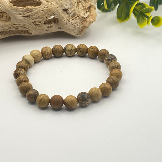 Beaded bracelet with natural stone beads on a white surface with decorative elements.