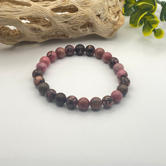 Round beaded bracelet with purple and brown stones on a white surface.