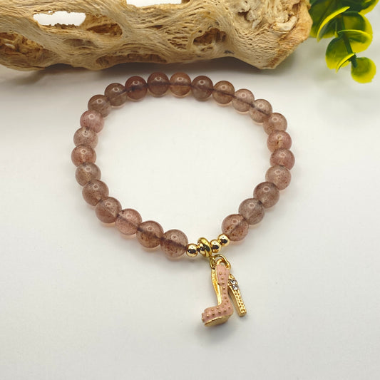 Beaded bracelet with a high heel charm on a light background