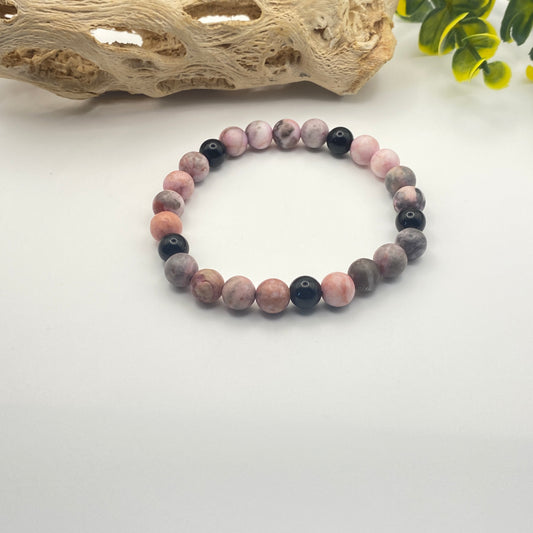 Beaded bracelet with pink and black beads on a white background