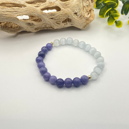 Beaded bracelet with purple and white beads on a white surface with natural elements.