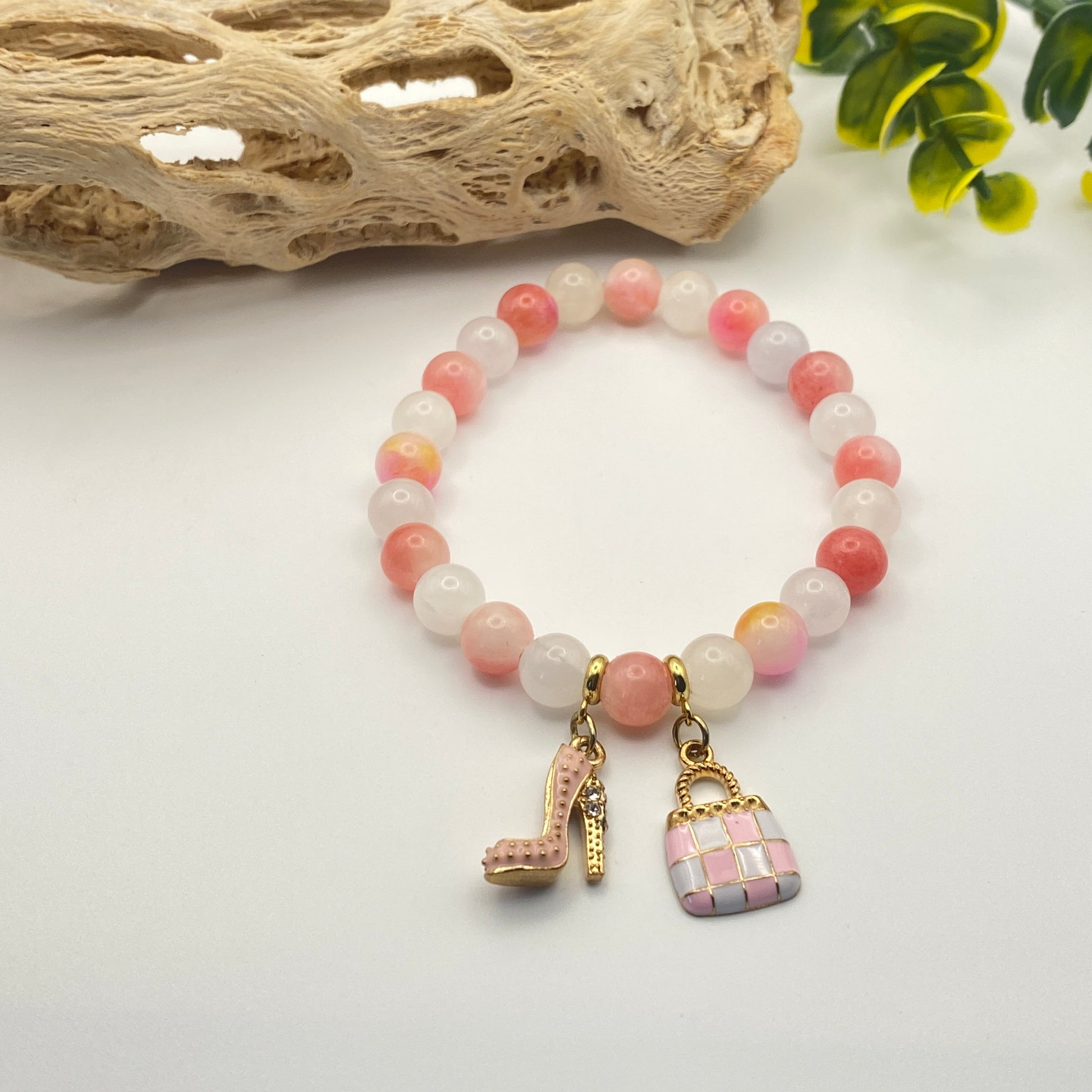 Bracelet with pink and white beads and decorative charms on a light background