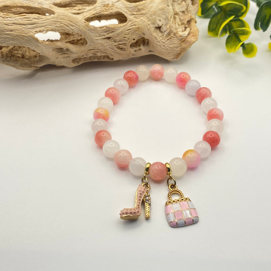 Bracelet with pink and white beads and decorative charms on a light background