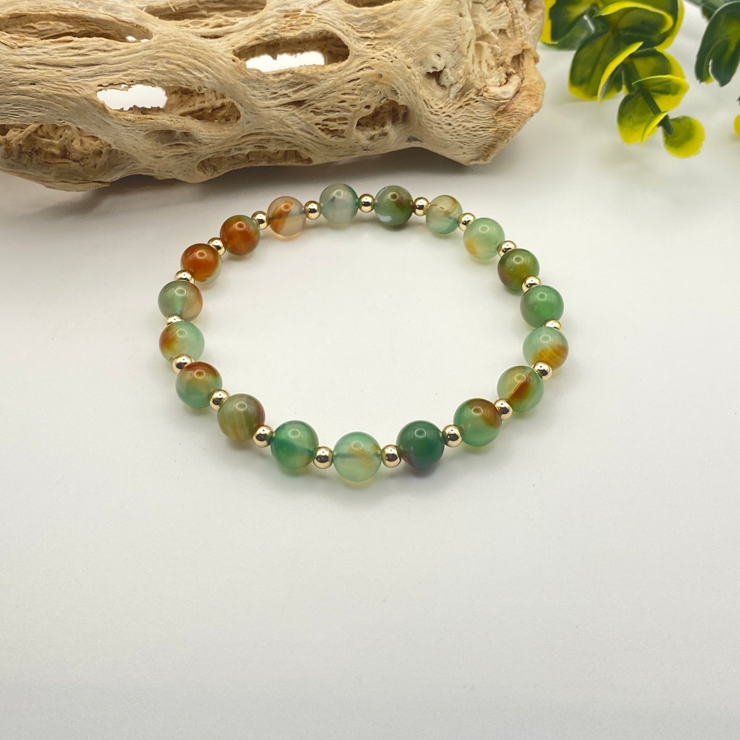 Beaded bracelet with green and gold beads on a white background