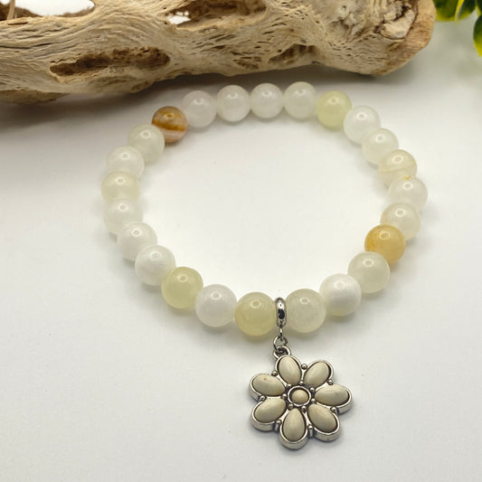 Beaded bracelet with a silver flower charm on a white background