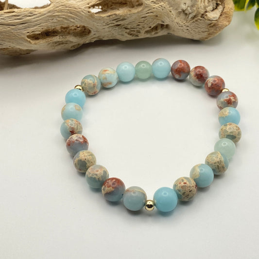 Multicolored beaded bracelet on a white surface with driftwood in the background