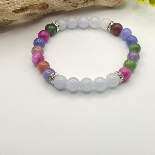 Multicolored beaded bracelet on a white surface with a natural wood piece in the background