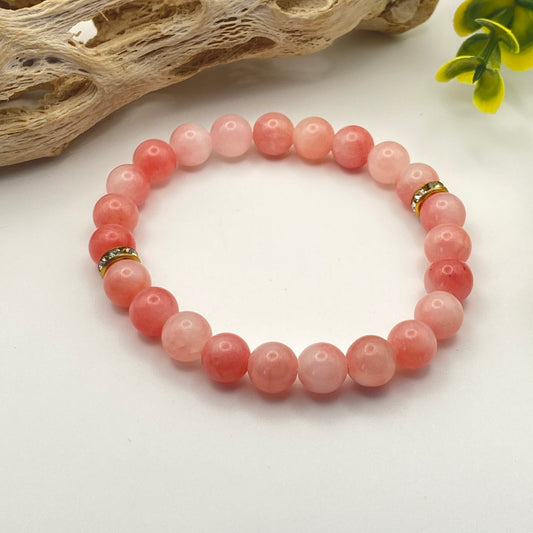 Pink beaded bracelet on a white background with natural elements