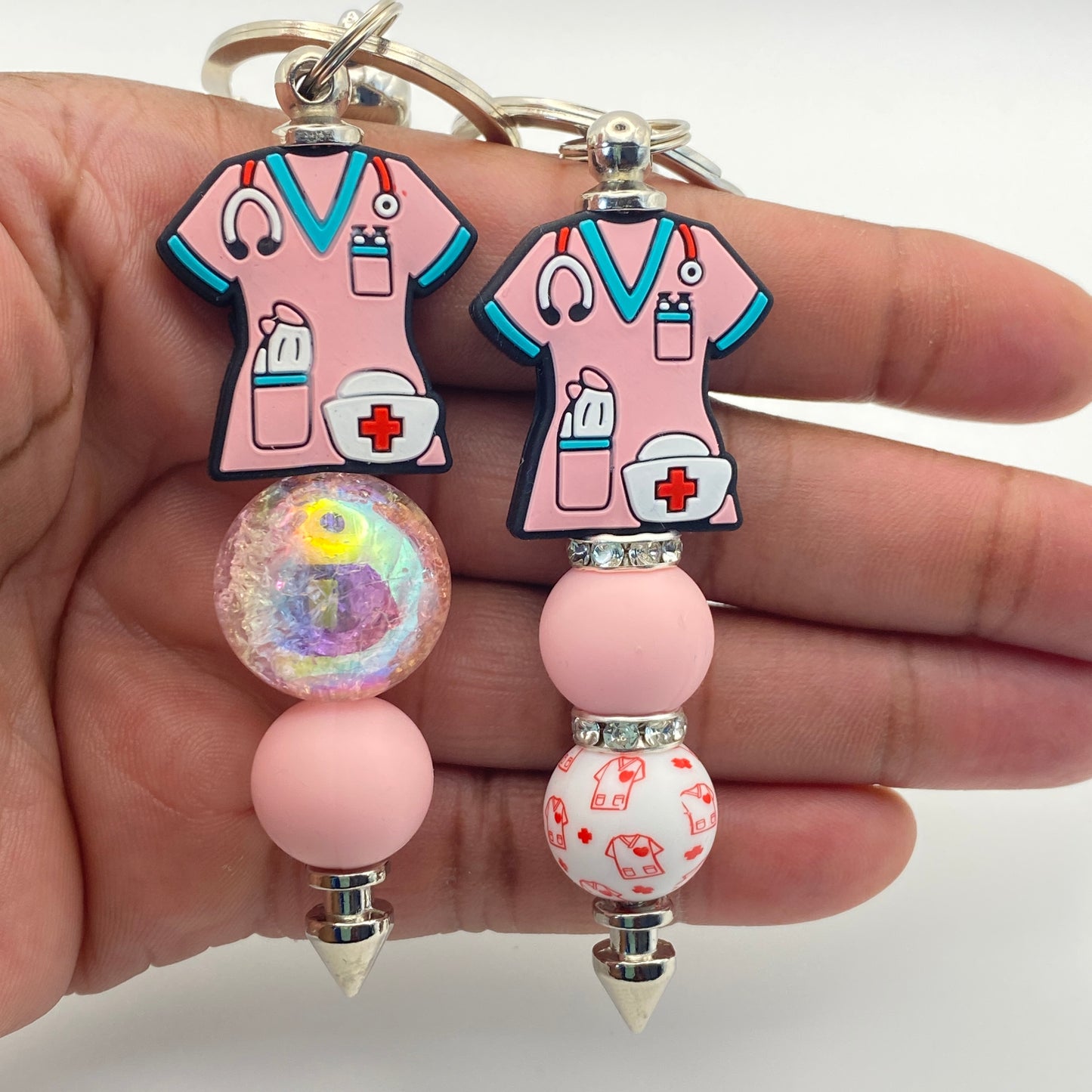 Keychain with pink nurse outfit design held by a hand on a white background
