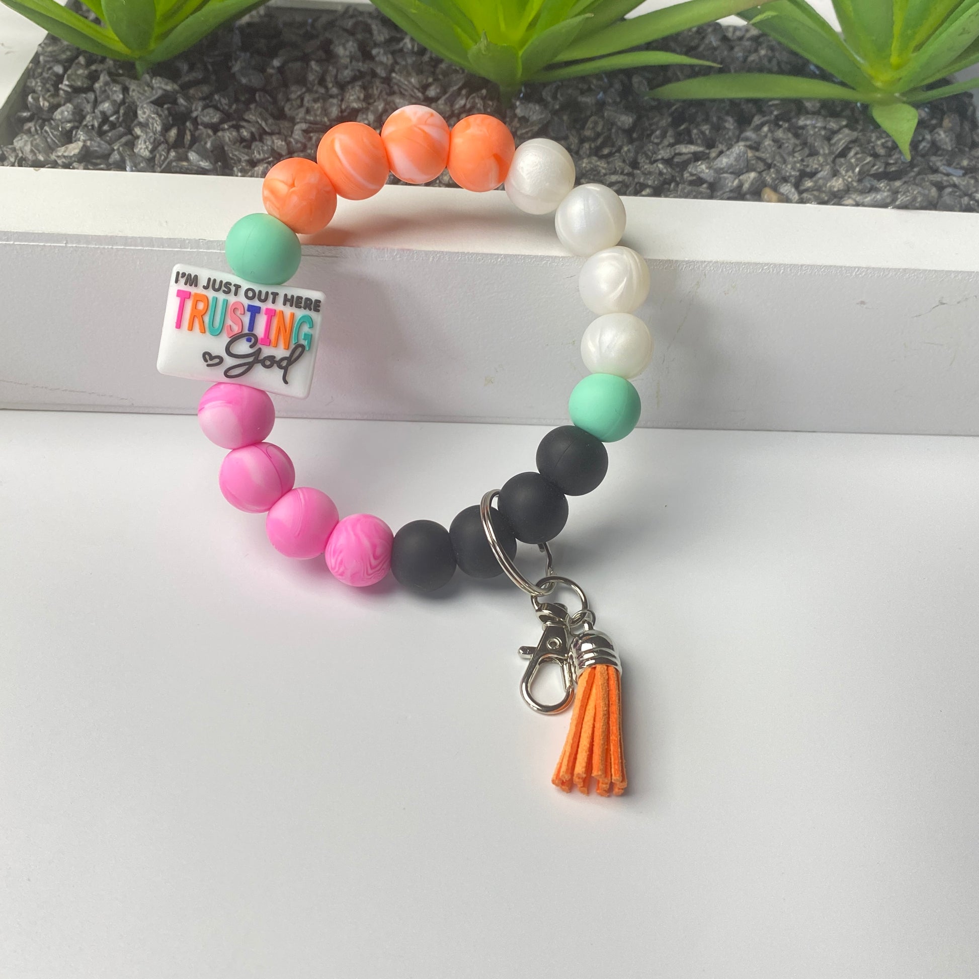 Colorful beaded bracelet with a tassel charm on a white surface