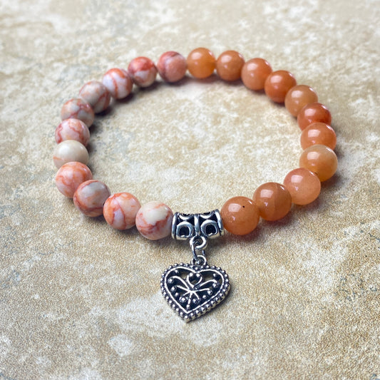 Beaded bracelet with a heart-shaped charm on a sandy background