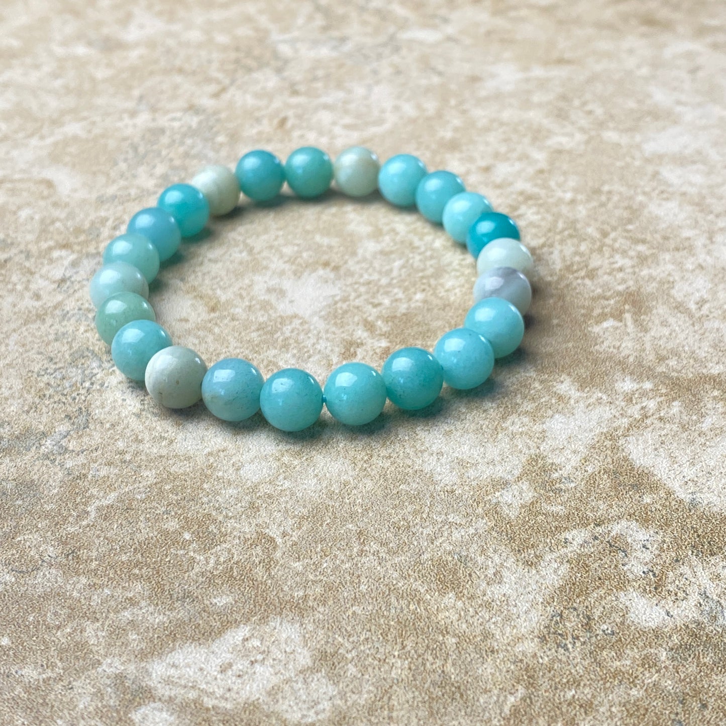 Beaded bracelet with blue and white beads on a textured beige surface