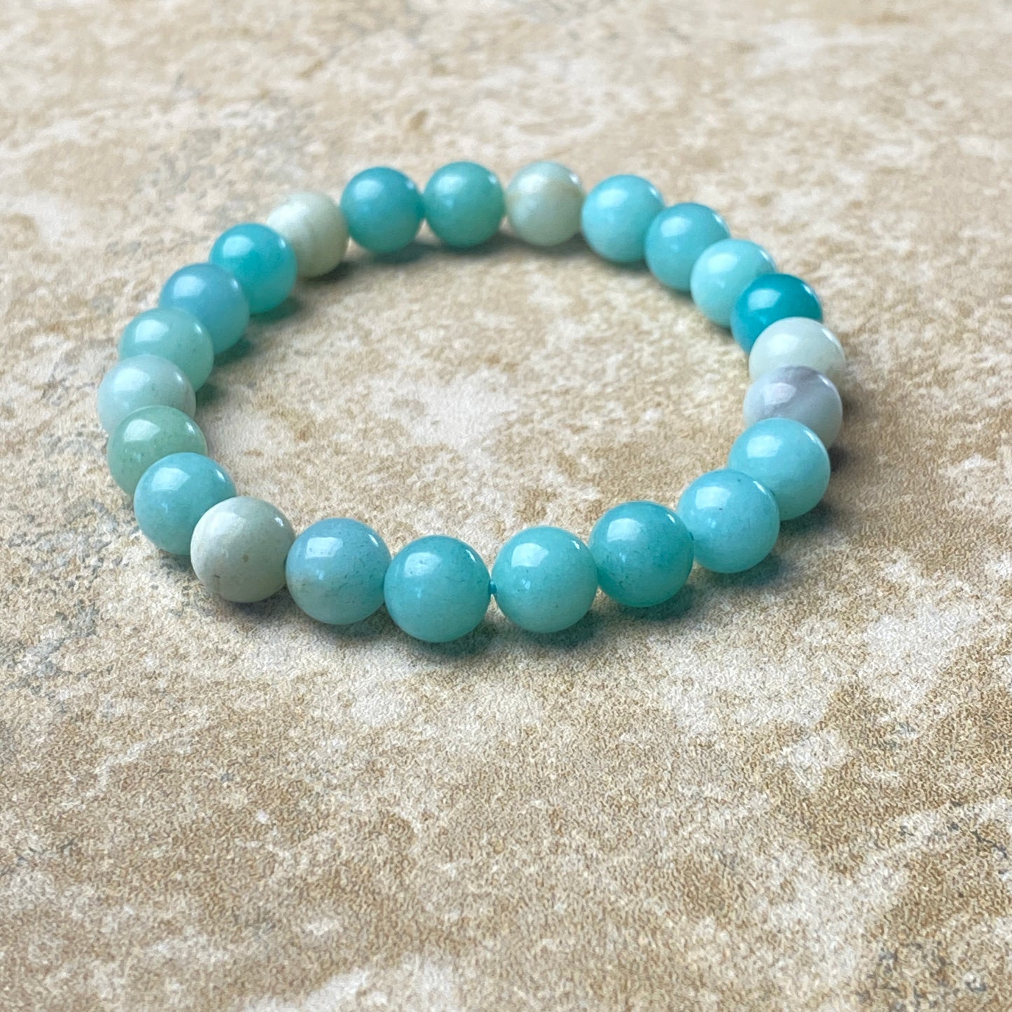 Beaded bracelet with blue and white beads on a sandy surface