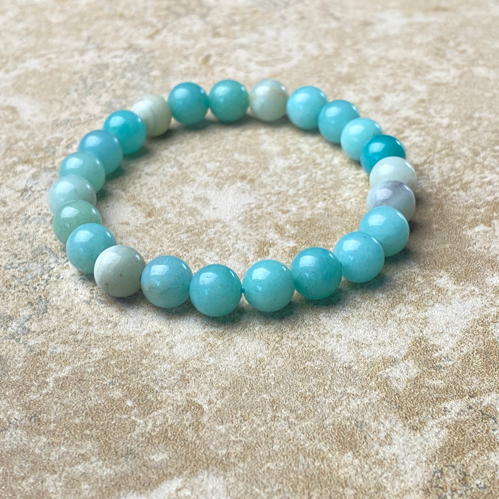 Beaded bracelet with blue and white beads on a sandy surface
