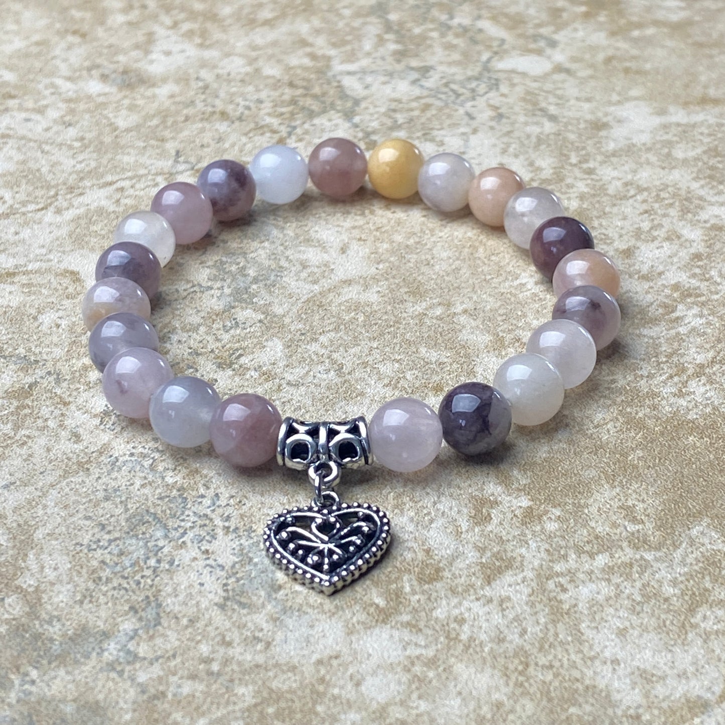 Beaded bracelet with a heart-shaped charm on a textured surface