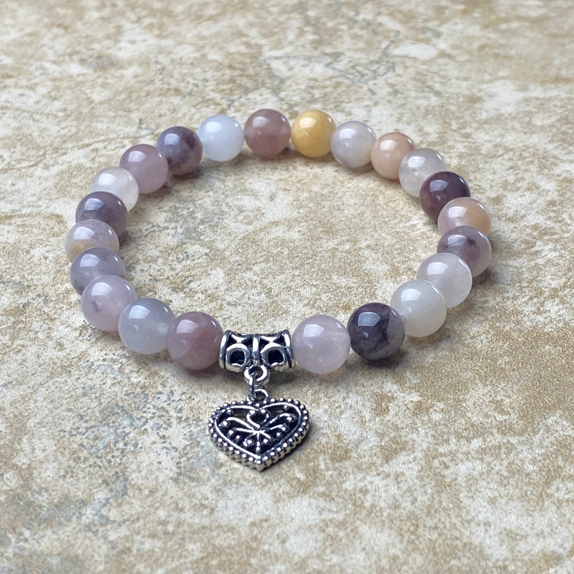Beaded bracelet with a heart-shaped charm on a textured surface