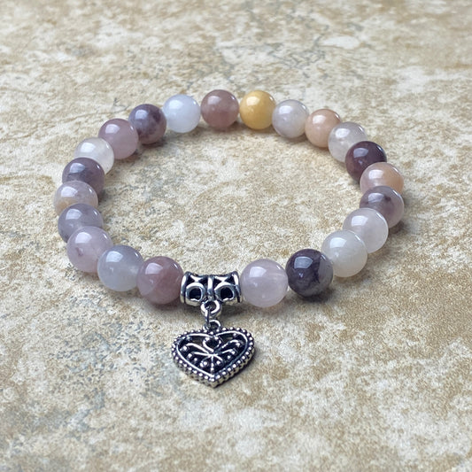 Beaded bracelet with a heart-shaped charm on a textured surface