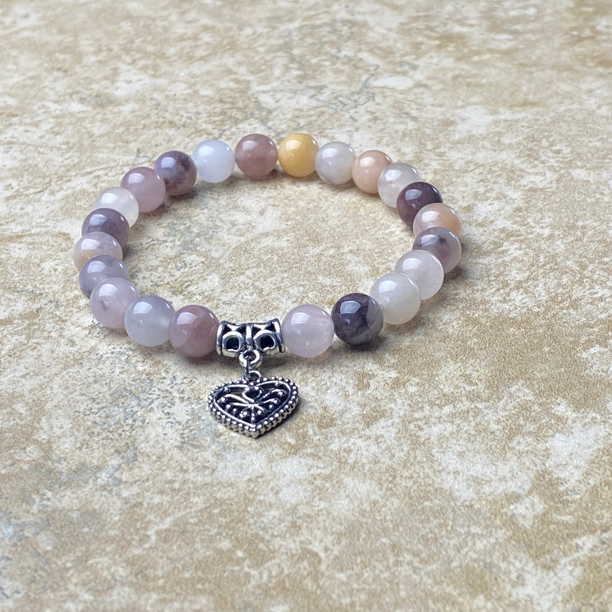 Beaded bracelet with a heart charm on a textured surface
