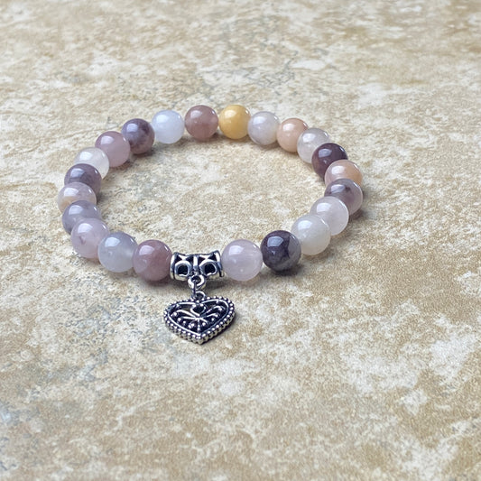 Beaded bracelet with a heart charm on a textured surface