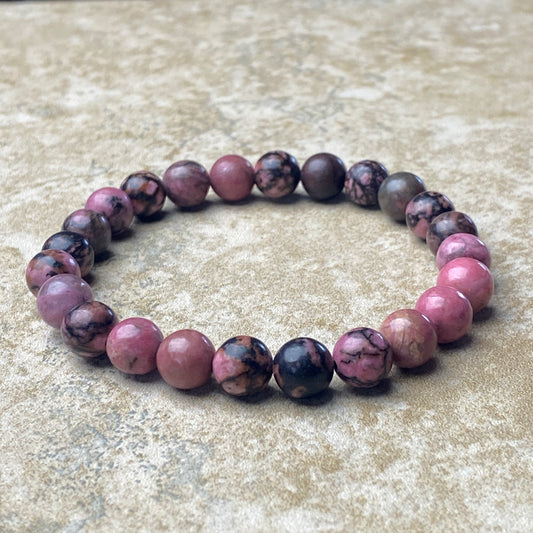 Beaded bracelet with pink and purple stones on a textured surface