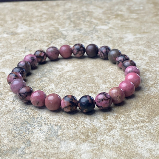 Beaded bracelet with pink and black beads on a textured surface