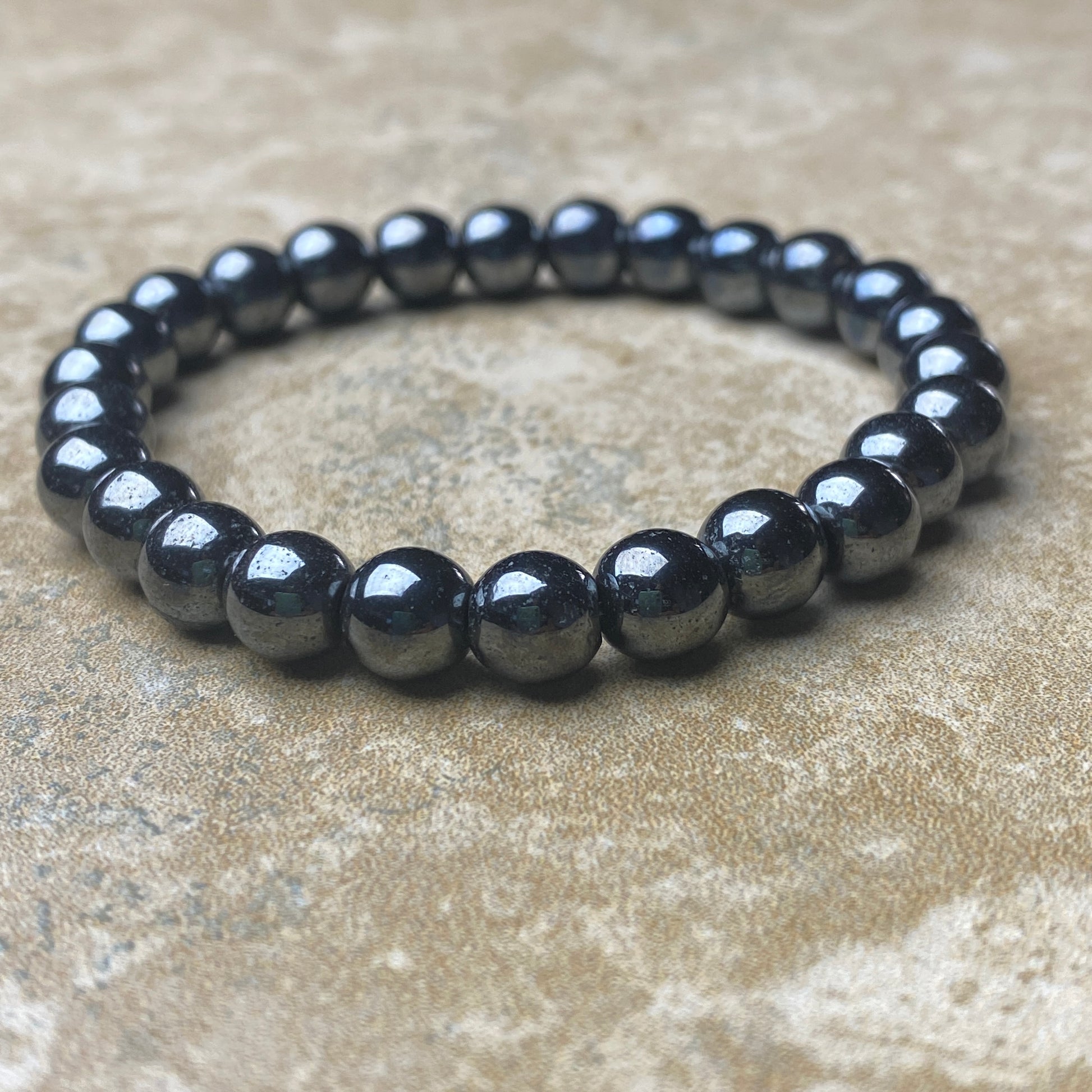 Black beaded bracelet on a textured beige surface