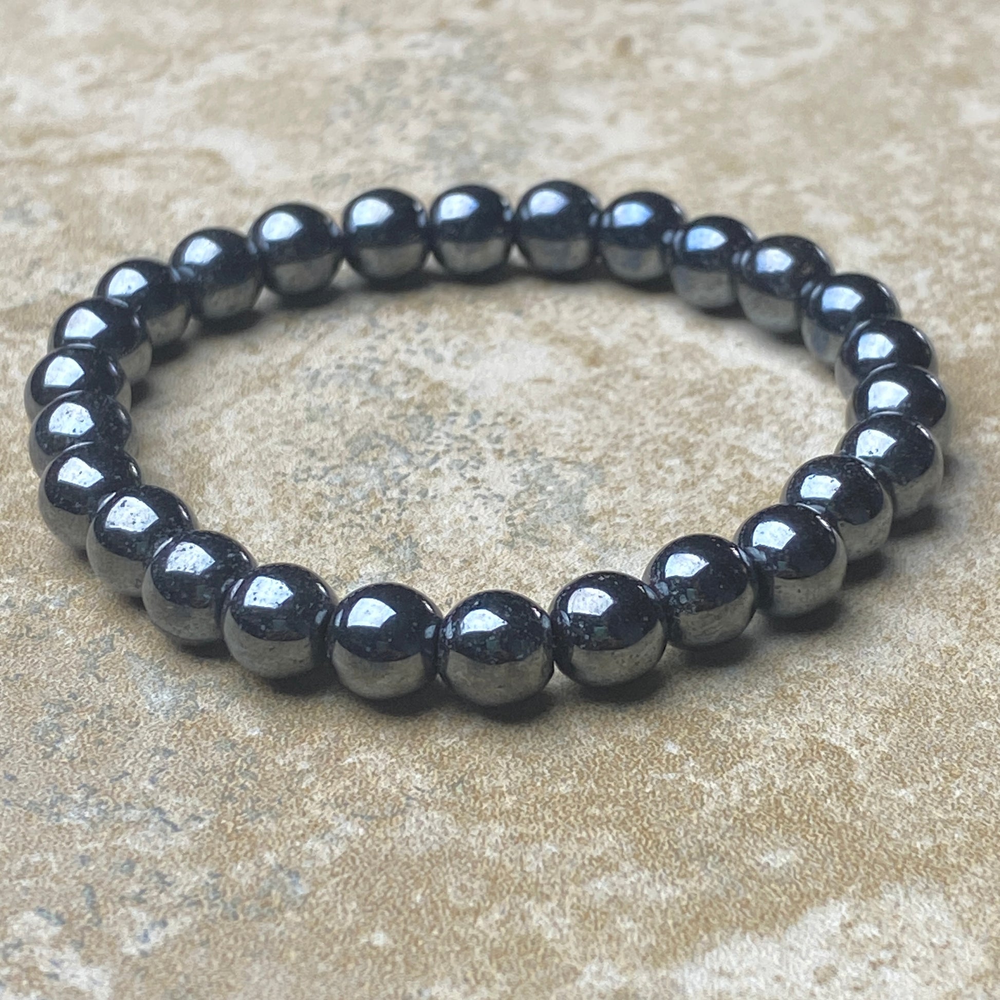 Black beaded bracelet on a beige surface