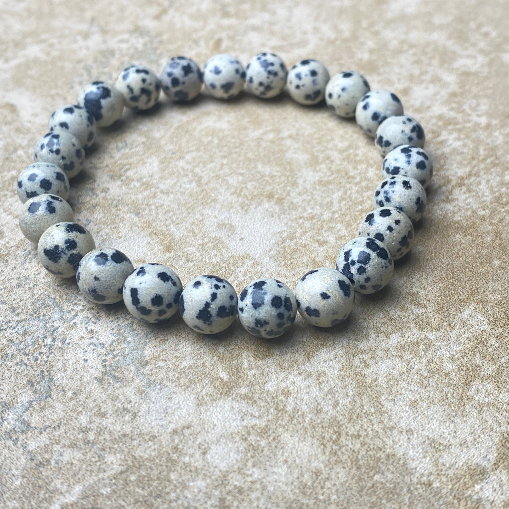 Bracelet made of white beads with black spots on a textured surface