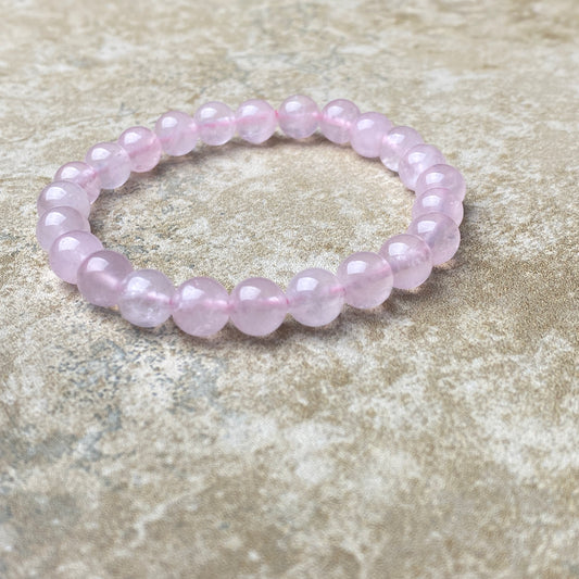 Pink beaded bracelet on a textured stone surface