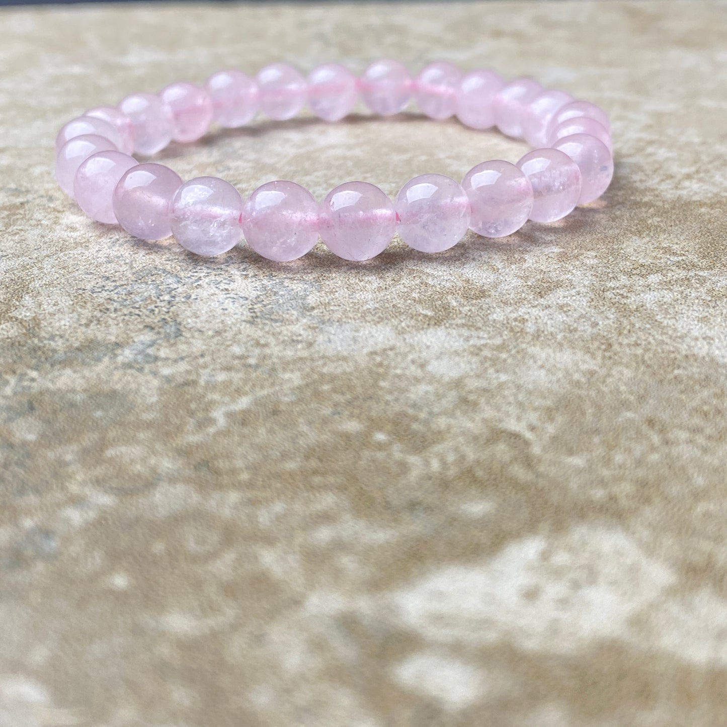 Pink beaded bracelet on a textured stone surface