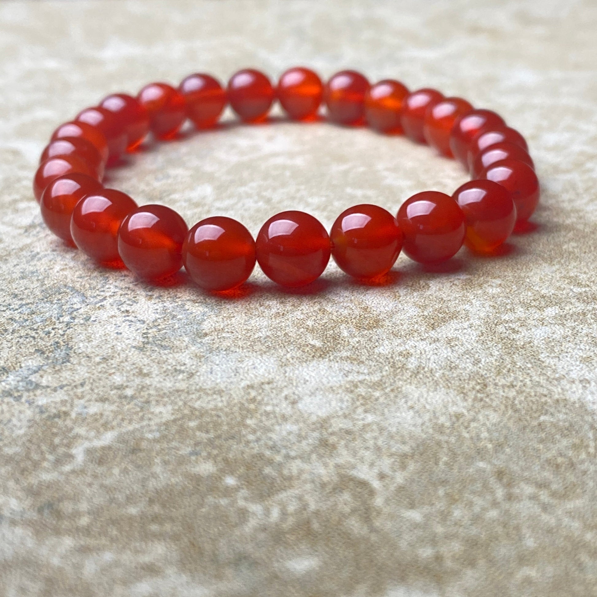 Red beaded bracelet on a textured beige surface
