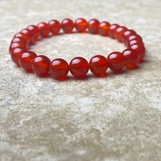 Red beaded bracelet on a textured beige surface