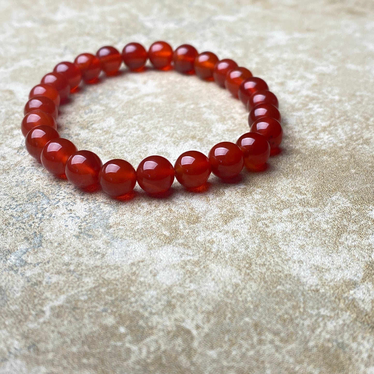 Red beaded bracelet on a textured beige surface