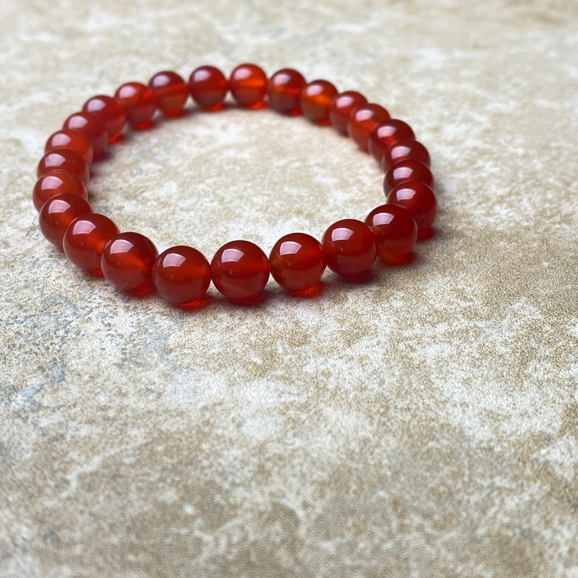 Red beaded bracelet on a textured beige surface